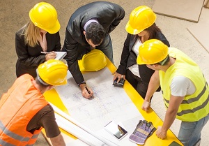 contractors gathered around a table looking at blueprints